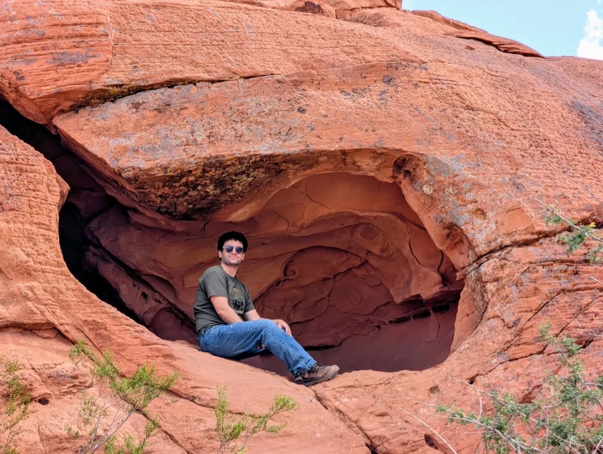 Traveler sitting in a red rock arch formation