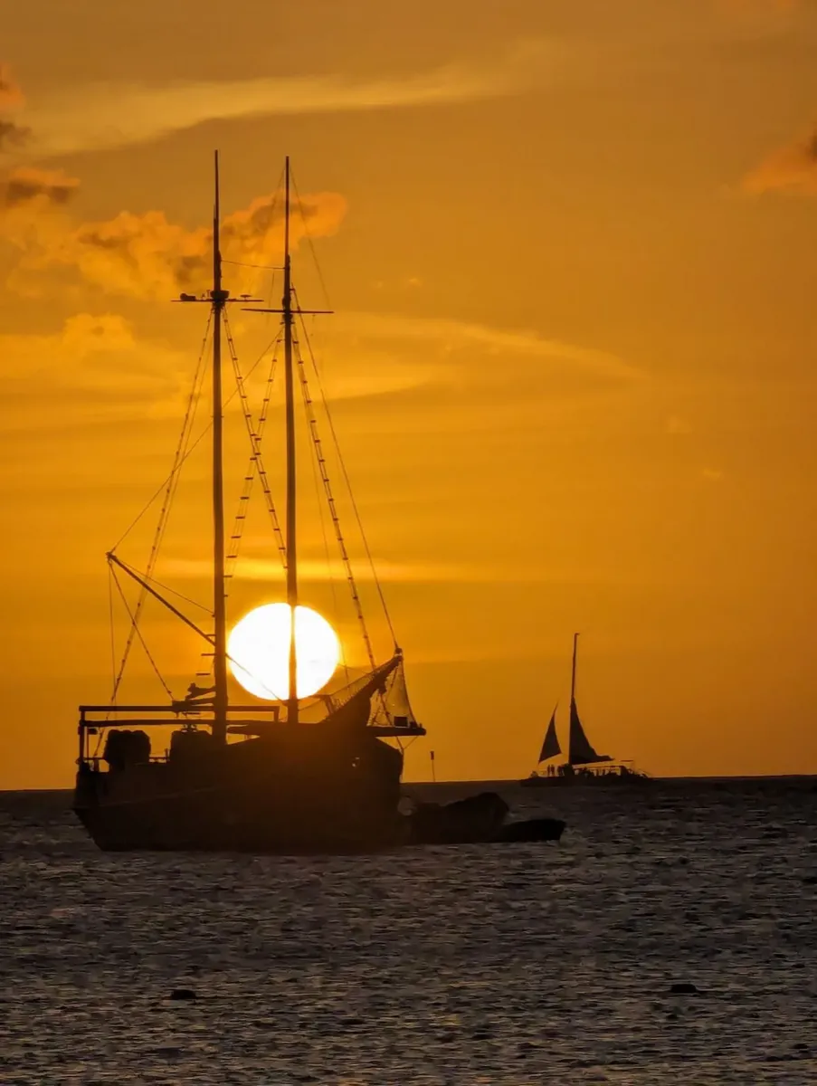 Sailboat silhouetted against a golden sunset
